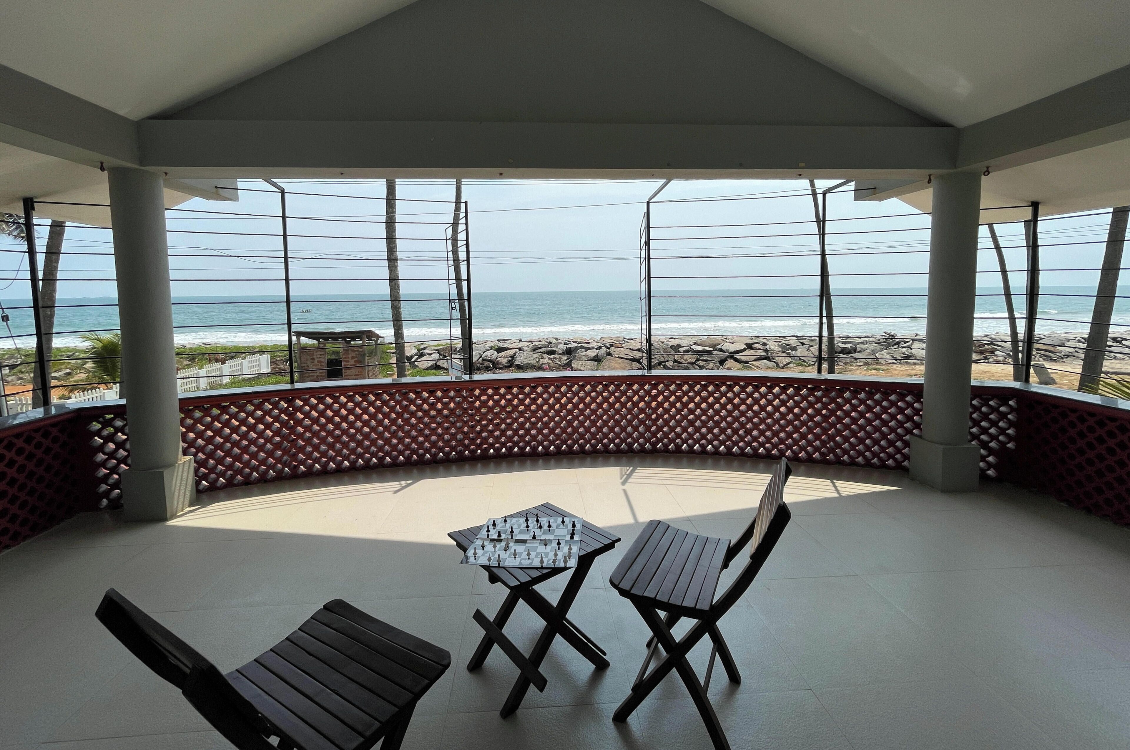 A covered outdoor seating area with a view of the beach and ocean.