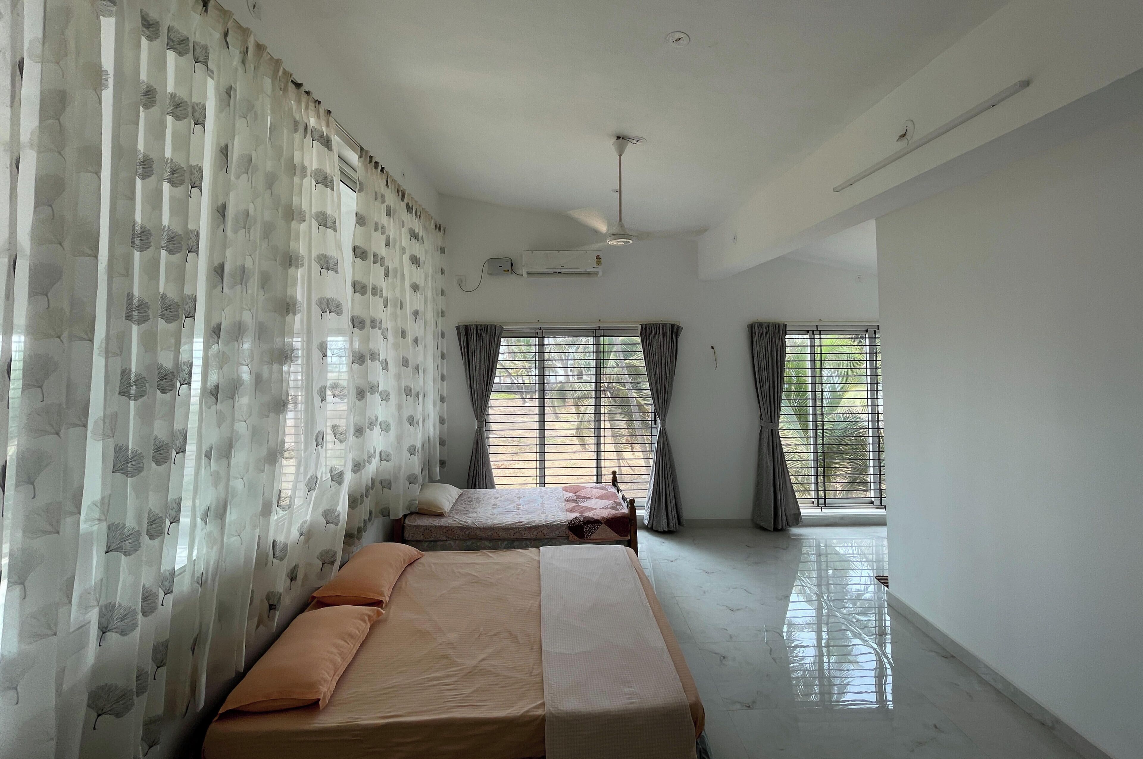 Una habitación con cama, ventilador de techo y ventanas con cortinas.