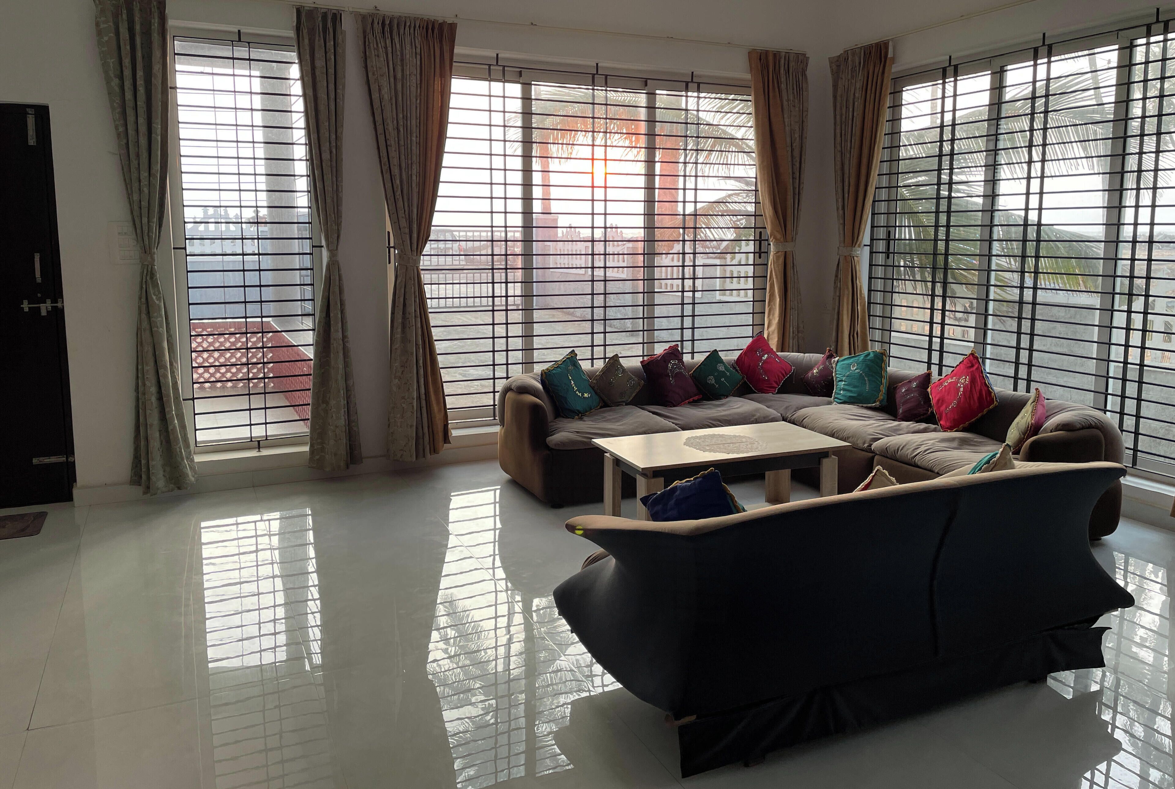 Una sala de estar con un juego de sofá, una mesa de centro y ventanas grandes con cortinas.