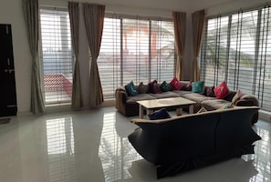 Una sala de estar con un juego de sofá, una mesa de centro y ventanas grandes con cortinas.