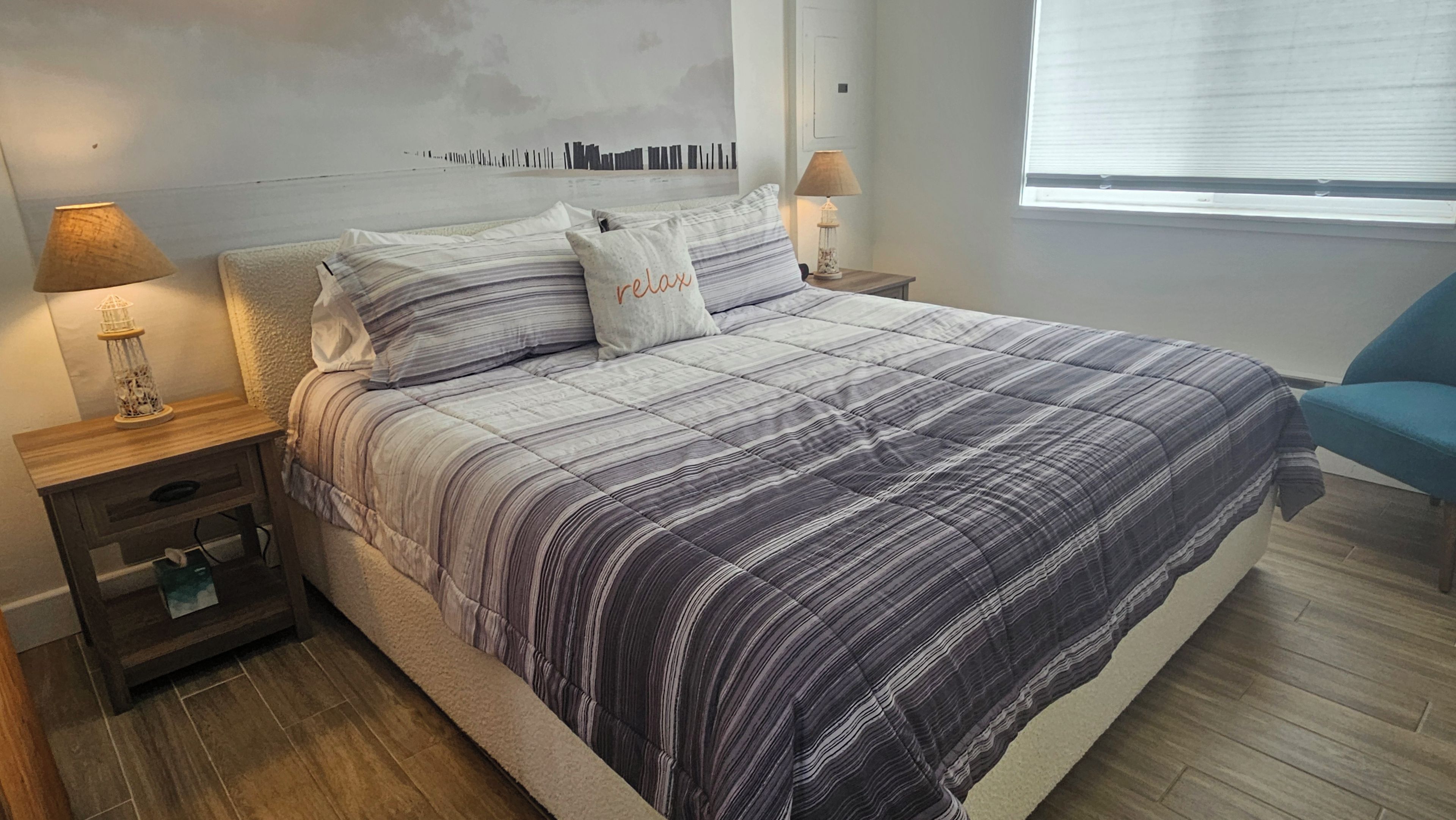 A bedroom with a bed, nightstands, a lamp, a chair, and a window.