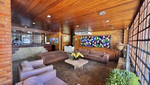 Eine Lobby mit Holzboden und Backsteinwänden, ausgestattet mit Sofas, einem Couchtisch und einem großen abstrakten Gemälde.