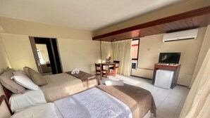 Ein Hotelzimmer mit zwei Betten, einem Schreibtisch, einem Fernseher und einer Klimaanlage.
