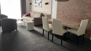 A modern living room with a sofa, ottoman, and dining table with chairs. - 150m from ski slopes, 1st floor, view ski slopes, swimming pool, balcony, tv, ski locker, 58m² (Eaux-Bonnes)