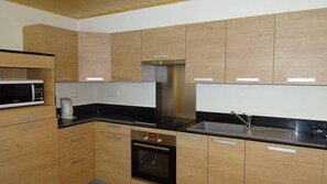 A modern kitchen with wooden cabinets, a stainless steel sink, and a built-in oven.