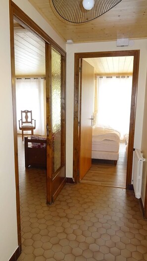 A room with a wooden floor, a bed, a chair, and a radiator.