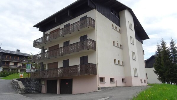 A multi-story building with balconies, a stone wall, and a sign indicating a ski resort.