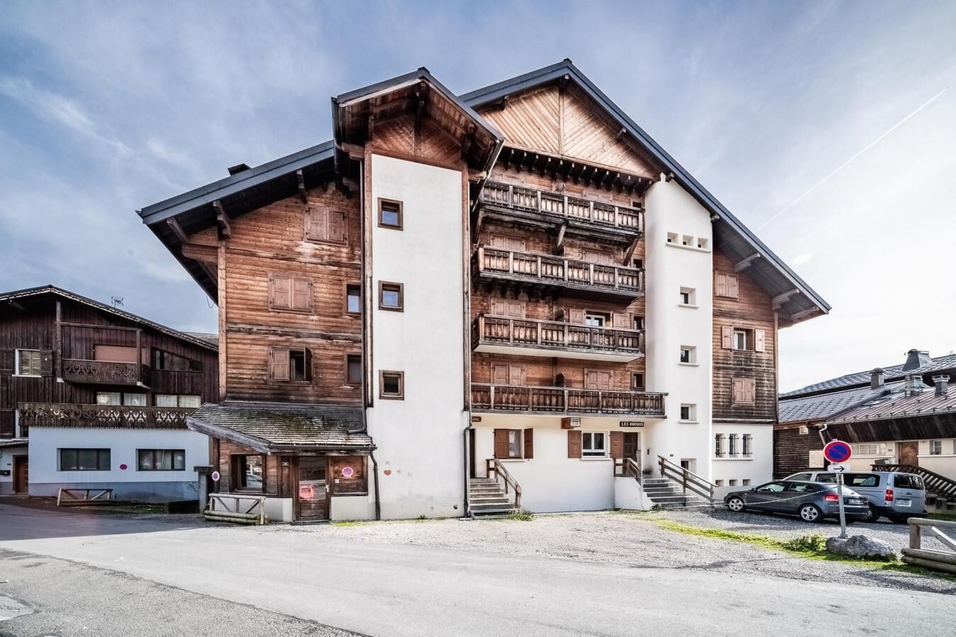 A multi-story building with wooden balconies and a white facade.