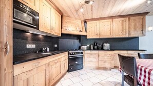 A kitchen with wooden cabinets, a black countertop, and a red and white checkered tablecloth. - Wifi, 200m from ski slopes, 4th floor, balcony, tv, ski locker, 105m², Les Gets (Les Gets)