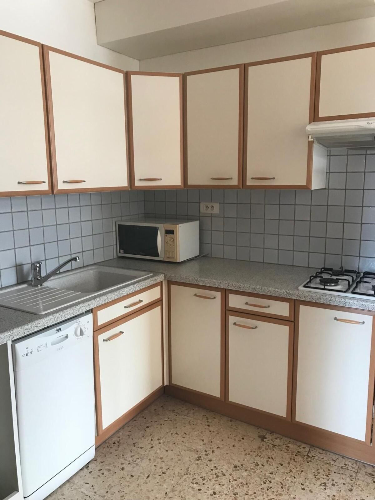 A kitchen with white cabinets, a microwave, a sink, and a dishwasher.