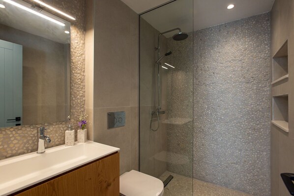 A modern bathroom with a glass-enclosed shower, a wooden vanity, and a large mirror.