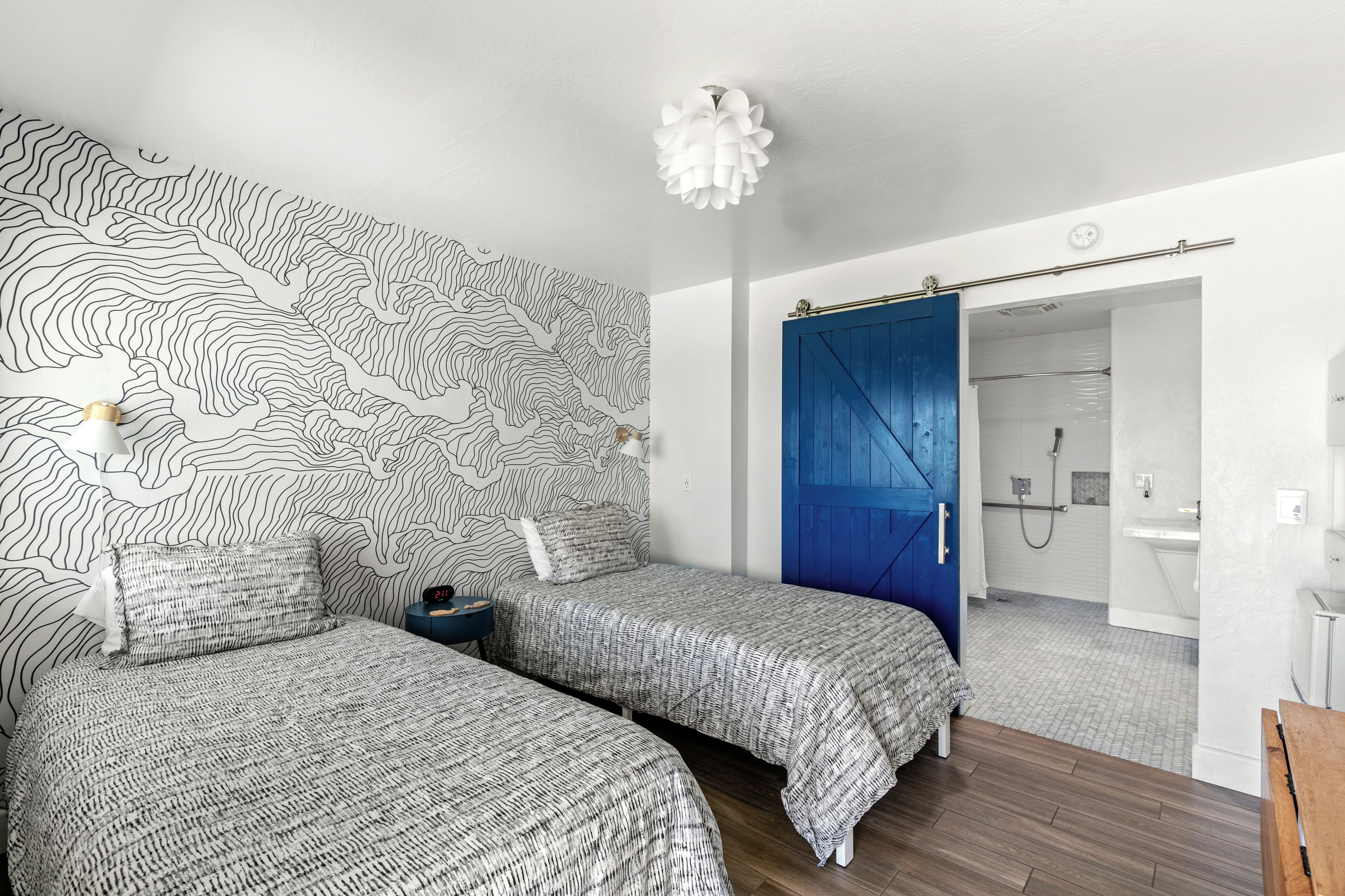 A bedroom with two beds, a blue door, and a bathroom visible through an open door.