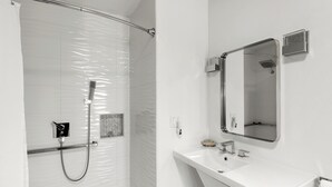 Une salle de bain moderne avec une douche, un lavabo et un miroir.