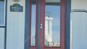 Un bâtiment sur lequel on peut lire l’inscription « Bureau du comptable », et dont la porte vitrée offre une vue sur un phare.