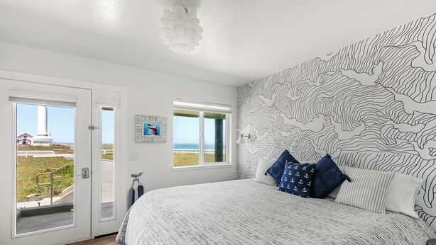 Une chambre dotée d’un grand lit, offrant une vue sur l’extérieur et dont un des murs est décoré d’un motif topographique.