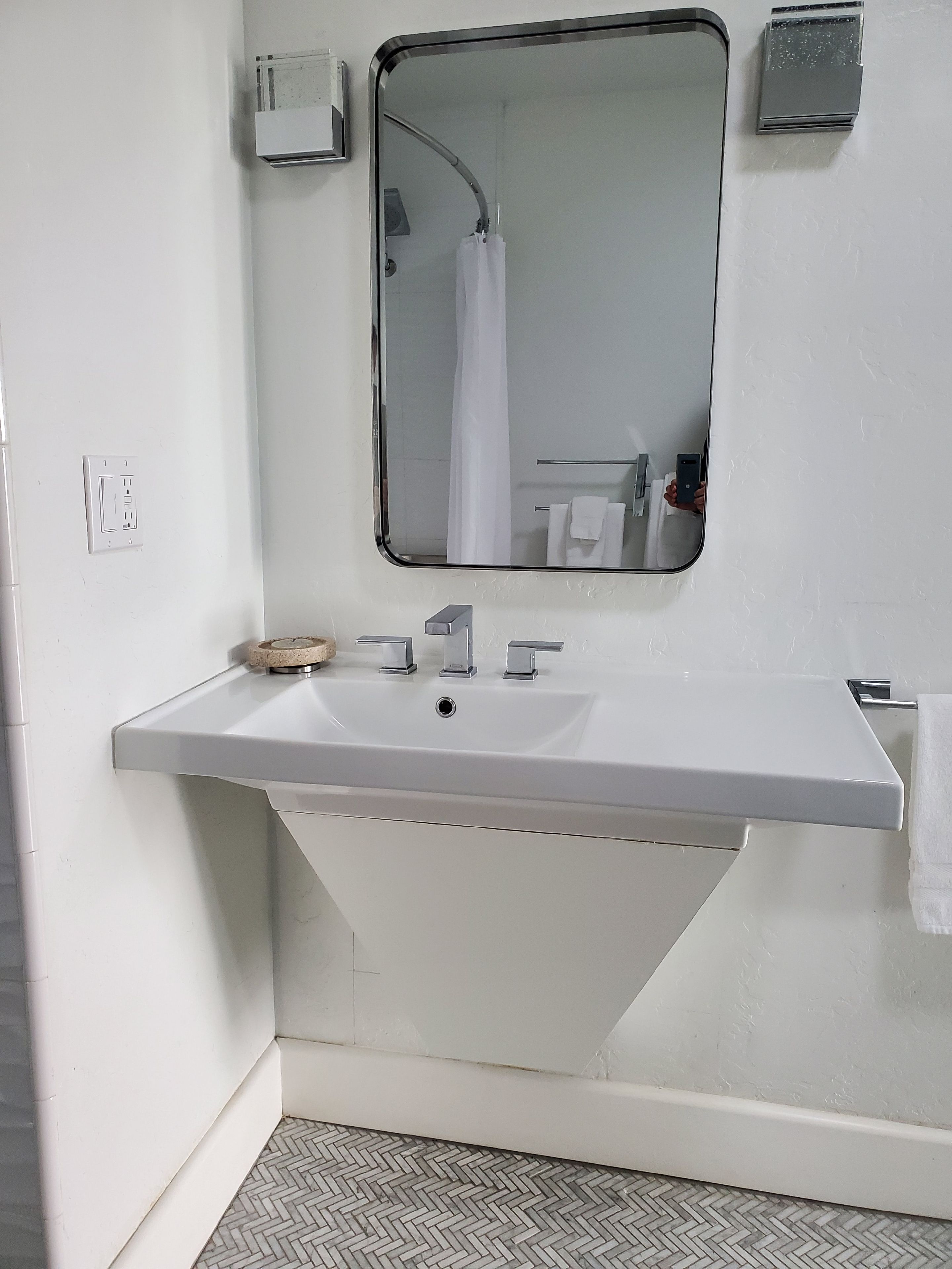 A bathroom with a white sink, a mirror, a towel rack, and a shower curtain.