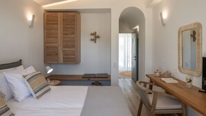 A modern bedroom with a bed, bedside table, chair, and a desk with a mirror.