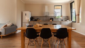 Una cocina moderna con una mesa de comedor de madera, sillas negras y un sofá gris.