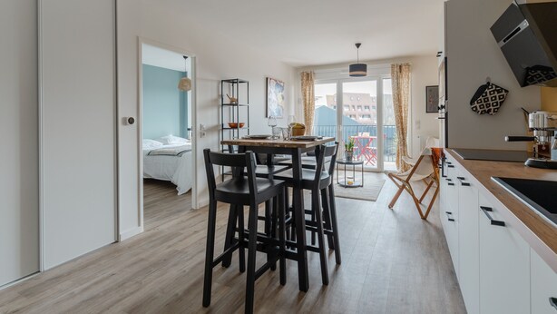 A modern kitchen with a dining area, a balcony with a view, and a separate bedroom. - Madreperla - Appt à moins d'un km de la plage (Courseulles-sur-Mer)