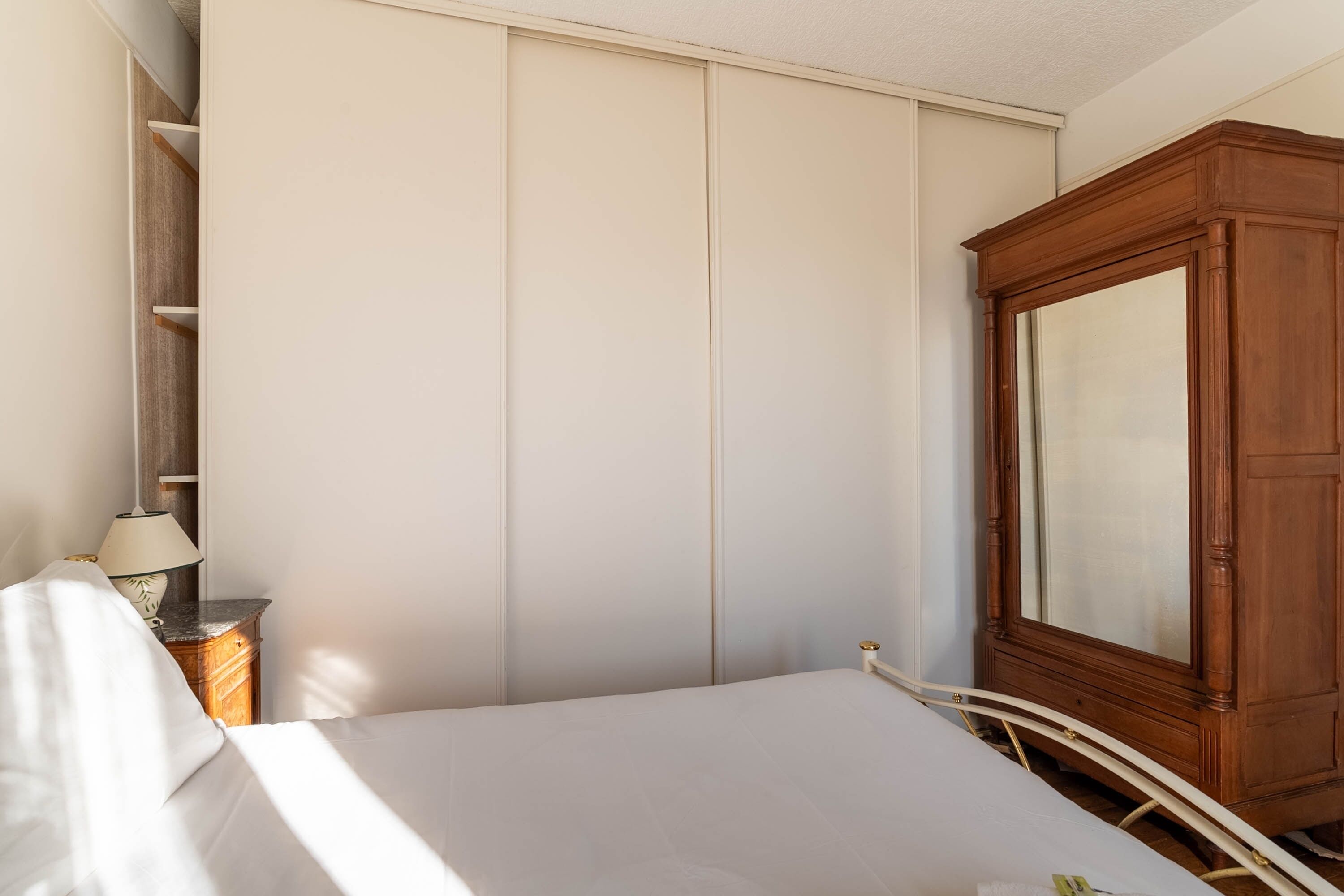 Un dormitorio con cama, un armario de madera y una mesita de noche con lámpara.