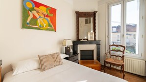 A bedroom with a large bed, a painting, a fireplace, and a chair. - Le Refuge de Charentonneau - A 30 min de Paris (Maisons-Alfort)