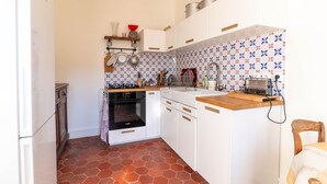 A compact kitchen with white cabinets, a wooden countertop, a built-in oven, and a patterned backsplash. - Le Refuge de Charentonneau - A 30 min de Paris (Maisons-Alfort)