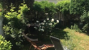A backyard with a hammock, a chair, and a small table. - Le Refuge de Charentonneau - A 30 min de Paris (Maisons-Alfort)