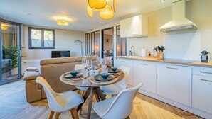 Une cuisine moderne avec des meubles blancs, un coin repas doté d’une table ronde et une grande fenêtre.