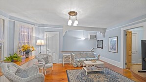 Un salon avec des meubles en osier, un tapis à motifs et un luminaire suspendu au plafond.