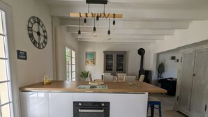 Eine moderne Küche mit Kochinsel, integriertem Backofen und Pendelleuchten.