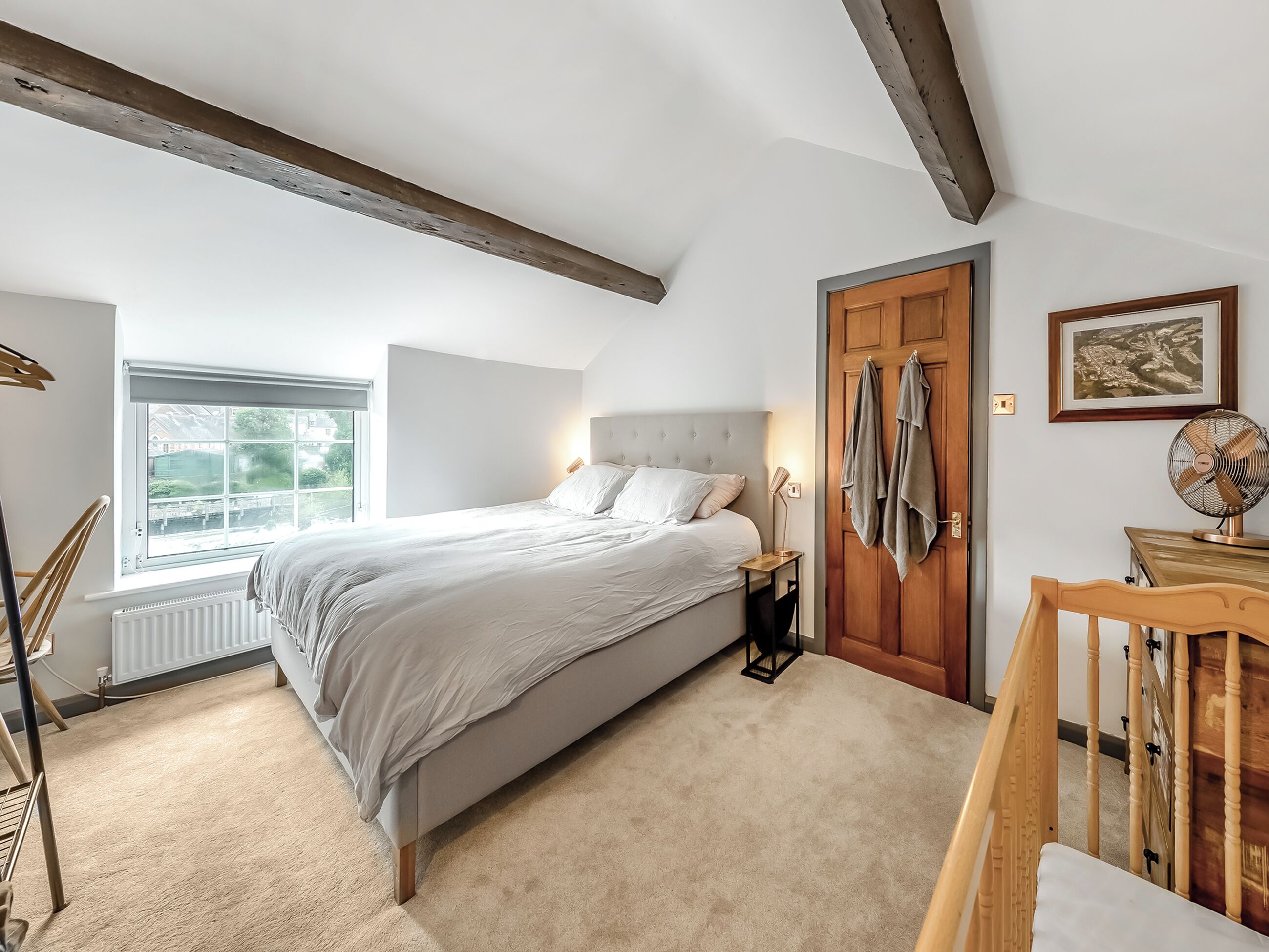 Une chambre à coucher avec un lit, une table de chevet, une porte en bois et une fenêtre.