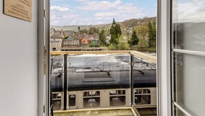 Blick aus einem Zimmer mit Fenster auf einen Fluss, eine Stadt und einen Hügel.