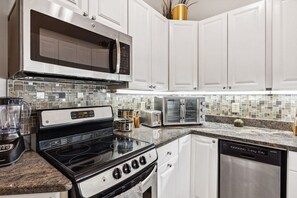A modern kitchen with white cabinets, a stainless steel microwave, a black stove, a toaster, and a dishwasher. - Redwood Retreat-RoofDeck/GameRoom/Walk to Downtown (Cleveland)