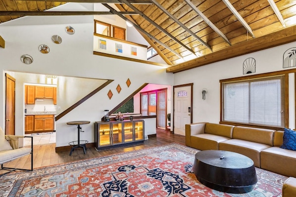 Un loft spacieux avec de hauts plafonds, un coin cuisine, un espace salon avec un canapé et un tapis à motifs.