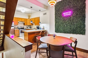 Une cuisine moderne avec des meubles en bois, un îlot central et un néon mural.