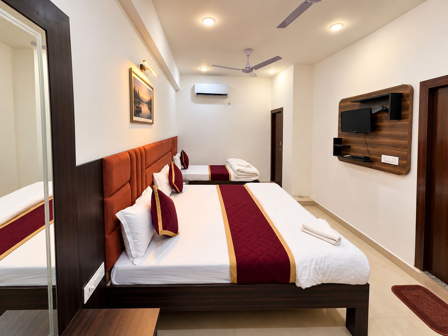 Ein Hotelzimmer mit einem großen Bett, einem an der Wand befestigten Fernseher und einem Deckenventilator.