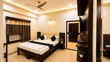 A modern bedroom with a bed, a ceiling fan, a television, and a door leading to another room.