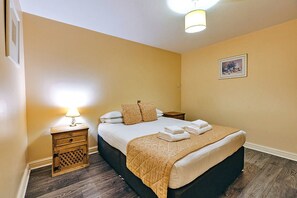 Une chambre d’hôtel avec un lit, des tables de chevet, une lampe et un tableau au mur.