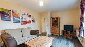 Een woonkamer met een bank, salontafel, tv-meubel en kunst aan de muur.