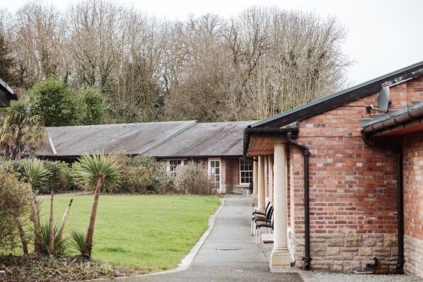 A brick building with a covered patio area and outdoor seating. - Netley Hall - Angelica (Dorrington)