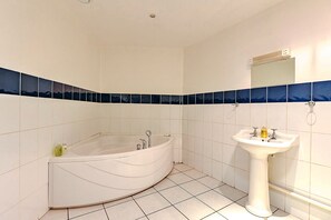 A bathroom with a freestanding bathtub, a pedestal sink, and blue-tiled walls.