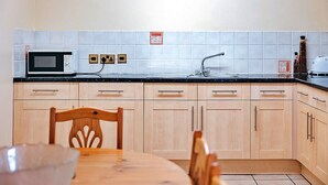 Una cocina con microondas, lavamanos y armarios de madera.
