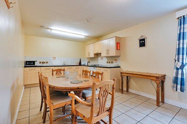 A compact kitchen with a dining table, chairs, and basic appliances.