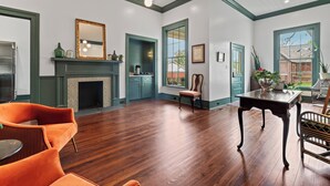 A spacious room with hardwood flooring, a fireplace, a dining table, and a large window with a view.