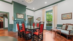 A dining room with a wooden table and chairs, a sofa, and a view of the outdoors.
