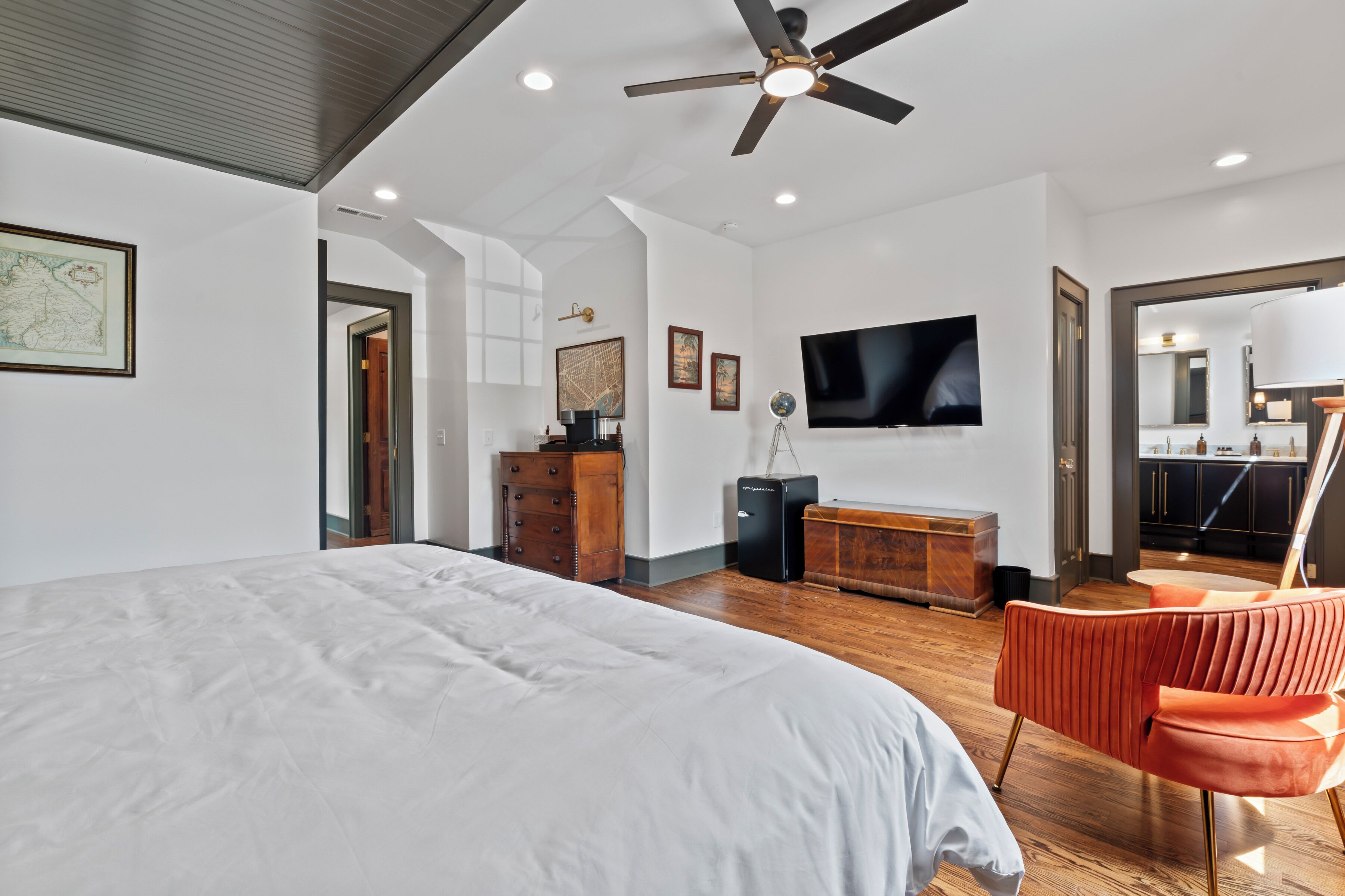 Une chambre à coucher avec un grand lit, un ventilateur de plafond, un téléviseur à écran plat et une commode en bois.
