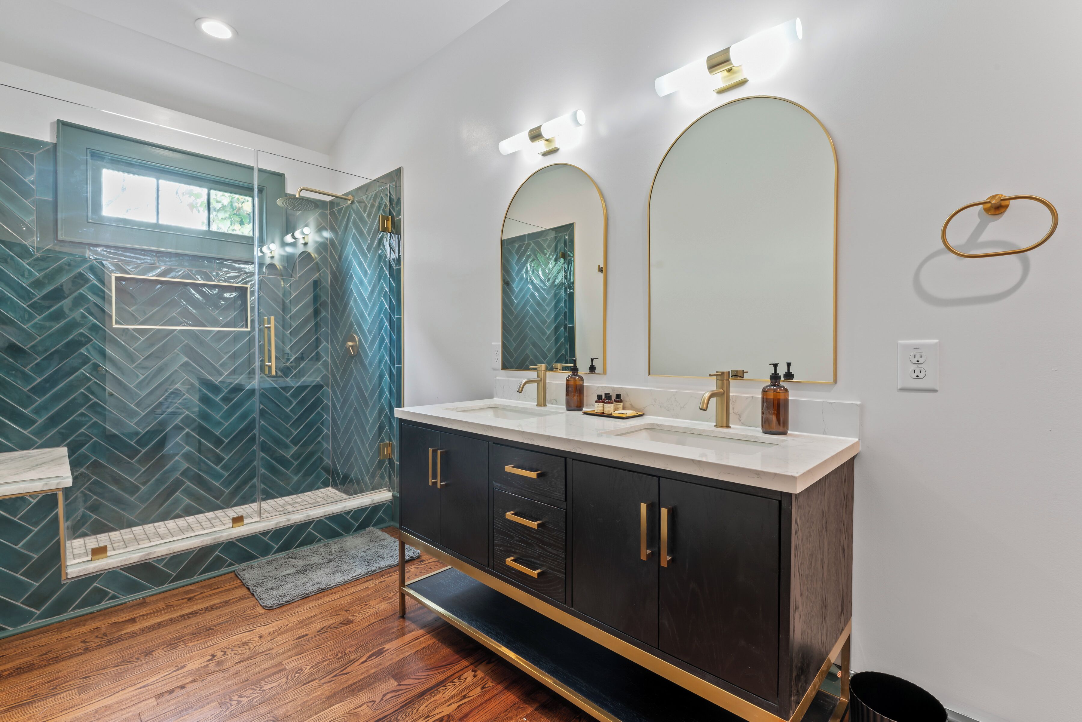 A modern bathroom with a glass-enclosed shower, a vanity with dual sinks, and a large mirror.