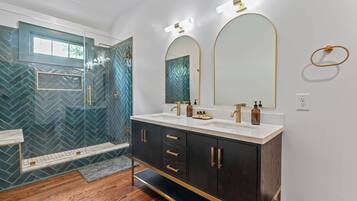 A modern bathroom with a glass-enclosed shower, a vanity with dual sinks, and a large mirror.