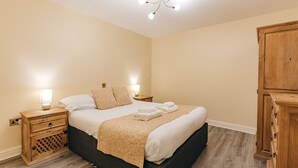 Une chambre à coucher comprenant un lit, des tables de chevet, une armoire et un lustre.