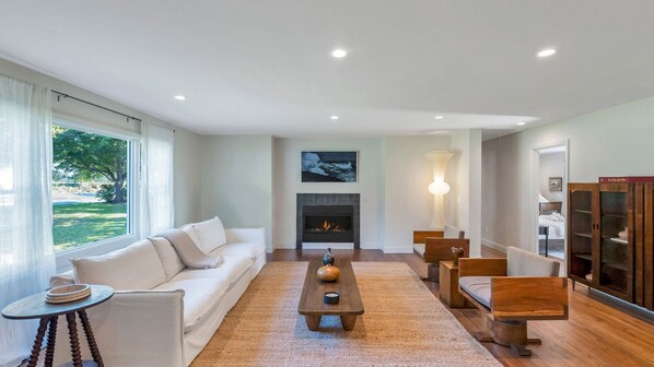 A modern living room with a fireplace, a sofa, a coffee table, and a bookshelf.